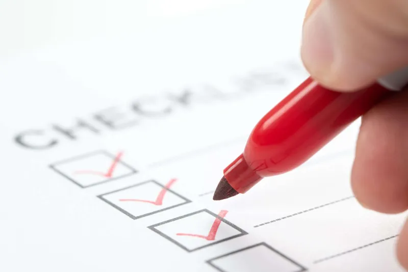 Hand with a red marker ticking a box on an on-page SEO checklist