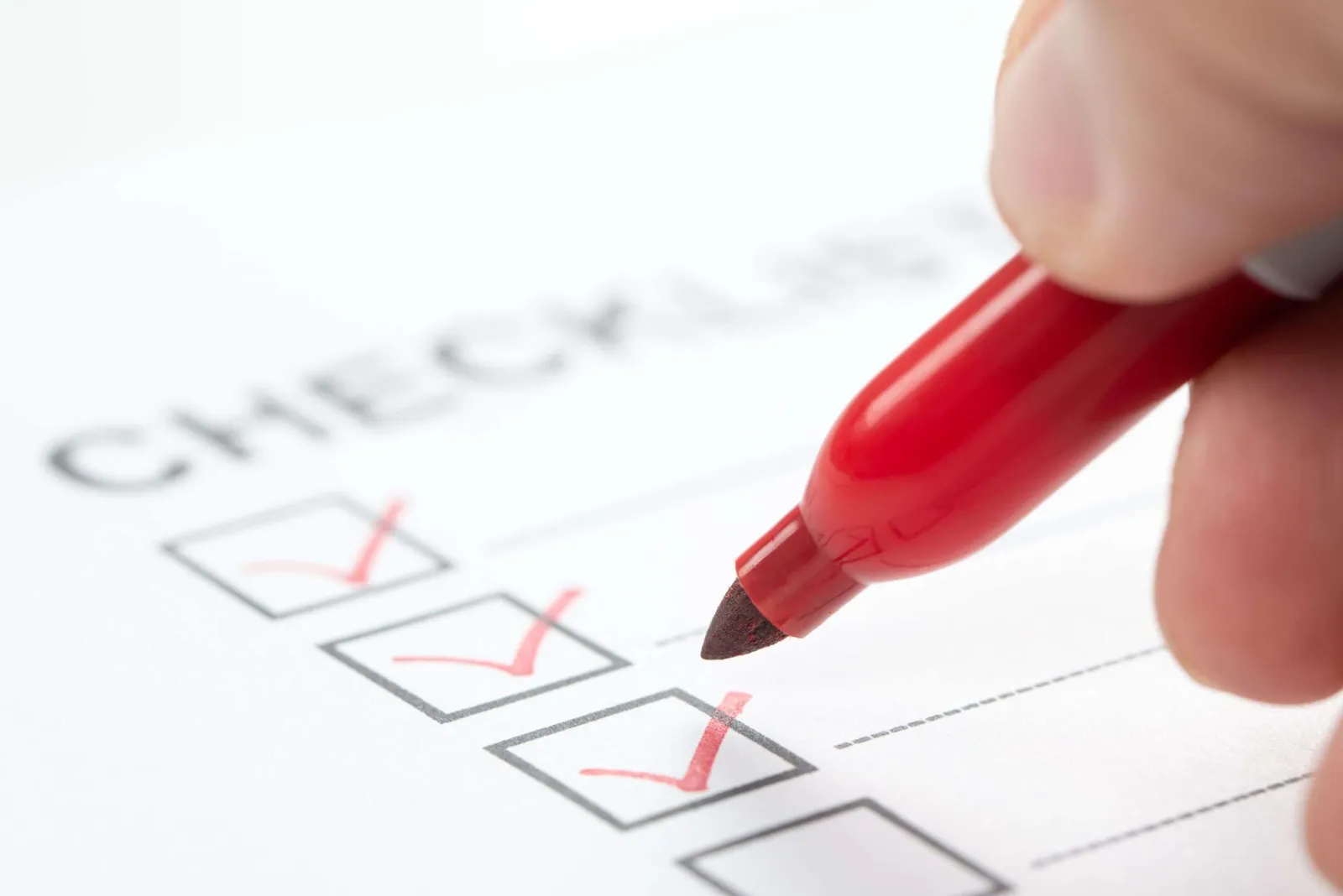 Hand with a red marker ticking a box on an on-page SEO checklist